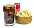 Glass of cold refreshing coca cola soda with ice, metal can of coca cola classic, wooden bowl of fresh caramel popcorn, isolated Royalty Free Stock Photo