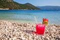 Glass of cold strawberry-daiquiri cocktail on the backgrond of Antisamos beach, Kefalonia island, Greece. Royalty Free Stock Photo