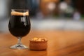 Glass of cold tasty dark beer served with peanuts on table Royalty Free Stock Photo