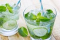 Glass of cold water with fresh mint leaves and cucumber with ice cubes on wooden background Royalty Free Stock Photo