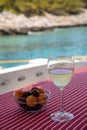 A glass of cold white wine and a bowl of cherries and apricots on the yacht table off the coast of Agistri island, Saronic Gulf, Royalty Free Stock Photo