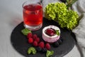 A glass with a compote of berries, next to a plate with blackberries, blueberries, raspberries.