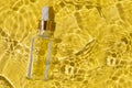 Glass container with beauty oil and pipette in yellow water