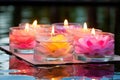 glass container with floating lotus candles on calm water