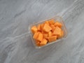 Glass container of sliced cantaloupe on a gray marble countertop