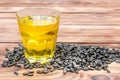 Glass of cooking oil with heap of sunflower seeds on wooden background Royalty Free Stock Photo