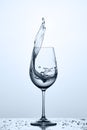 Glass of cool cleaner splashing water while standing on the glass with water bubbles against light background. Royalty Free Stock Photo