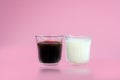 Glass of cool fresh milk, black coffee with reflection on pink background. Beverage in morning concept Royalty Free Stock Photo