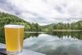 Glass of cool wheat light beer with lake background Royalty Free Stock Photo