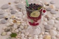 Glass with a cooling drink of berries and ice. Misted glass. Air bubbles on glass. A slice of lemon on a plate on the background