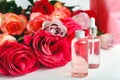 Glass cosmetic bottles, serum, soap, oil on white table floral background. Flower red pink roses natural organic beauty product.