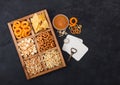 Glass of craft lager beer and opener with box of snacks on black background. Pretzel,salty potato sticks, peanuts, onion rings Royalty Free Stock Photo