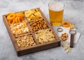 Glass of craft lager beer and opener with box of snacks on light background. Pretzel,salty potato sticks, peanuts, onion rings Royalty Free Stock Photo