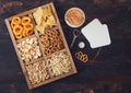 Glass of craft lager beer and opener with box of snacks on wooden background. Pretzel,salty potato sticks, peanuts, onion rings Royalty Free Stock Photo