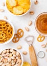 Glass of craft lager beer with snack and opener on stone kitchen table background. Pretzel and crisps and pistachio in white ceram Royalty Free Stock Photo