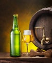 Glass of craft pale lager beer, beer bottle and wooden cask on the wooden table in the cellar