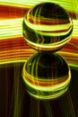 Glass crystal ball on a mirror surface with a yellow and red pattern light painting Royalty Free Stock Photo