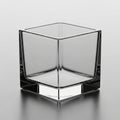 Glass cube with smooth, transparent surfaces is placed on a reflective, gray Royalty Free Stock Photo
