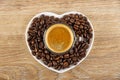 Cup with black coffee on roasted coffee beans in saucer in heart shape on wooden table. Top view Royalty Free Stock Photo
