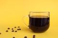 Glass cup with black coffee on yellow background