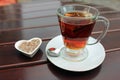 Glass cup of black tea including swimming tea bag and heart shaped bowl with sugar Royalty Free Stock Photo