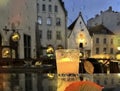 Glass cup with candle light on table on medieval street evening blurred bokeh light under rain drops on window in Tallinn old tow Royalty Free Stock Photo