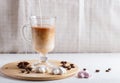Glass cup of coffee with cream poured over and meringues on a wooden board on a white background Royalty Free Stock Photo