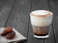 Glass cup of coffee with milk on a dark wooden background. Hot latte or cappuccino prepared with milk on a rustic wooden table