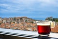 Glass cup of coffee or tea on balcony with view on Dubrovnik city center. View from above of red rooftops, historic old town and