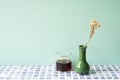 Glass cup of coffee with vase of dry flower on blue tile desk. mint wall background Royalty Free Stock Photo