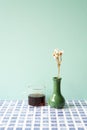 Glass cup of coffee with vase of dry flower on blue tile desk. mint wall background Royalty Free Stock Photo
