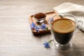 Glass cup of delicious chicory drink and flowers on wooden table, closeup. Space for text
