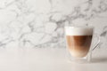 Glass cup of delicious layered coffee on white table against marble background, space for text Royalty Free Stock Photo