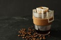 Glass cup with drip coffee bag and beans on black table, closeup Royalty Free Stock Photo