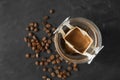 Glass cup with drip coffee bag on black table, top view