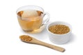 Glass cup with Fenugreek tea and a spoon and bowl with Fenugreek seeds on white background