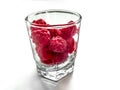Glass cup filled with red raspberries, close-up, isolated on a white background. Ripe juicy red fruits in a transparent bowl, Royalty Free Stock Photo
