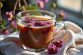 Glass cup of floral tea with blossoms in sunlit setting Royalty Free Stock Photo