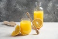 A glass cup of fresh orange juice with a wooden dipper