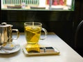 Glass Cup with Freshly Brewed Steaming Hot Green Tea with Pot Honey Smartphone on Table by Window in Cafe Royalty Free Stock Photo
