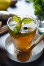 Glass cup of ginger tea with lemons and mint leaves on dark background. Ginger tea, drink ingredients, cold and autumn time