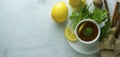 Glass cup of ginger tea with lemons and mint leaves on light background. Ginger tea, drink, cold and autumn time. Banner