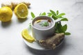 Glass cup of ginger tea with lemons and mint leaves on light background. Ginger tea, drink ingredients, cold and autumn time Royalty Free Stock Photo