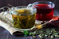 Glass cup of green herbal hot tea and cup of red hibiscus tea with dry leaves with fresh green leaves of mint. Royalty Free Stock Photo