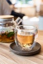 Glass cup with green or herbal tea and teapot on wooden table in cafe. Tea with mint and rose petals. Blurred background Royalty Free Stock Photo
