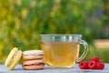 Glass cup of green tea with delicious macaroons cakes of different color and raspberries Royalty Free Stock Photo