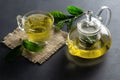 Glass cup of green tea with fresh tea leaves on wooden table Royalty Free Stock Photo