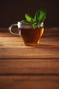 Glass cup of herbal tea with fresh mint on wooden table with brown background. Vertical shot with copy space Royalty Free Stock Photo