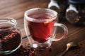 Glass cup of hot aromatic red fruit tea, jar of natural fruit tea with hibiscus petals, fruit slices and berries. Royalty Free Stock Photo