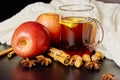 Glass cup of hot spicy drink with apple and orange slices, cinnamon and anise on brown wooden background Royalty Free Stock Photo